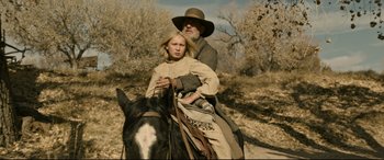 Movie still from “News of the World” (2020), directed by Paul Greengrass – A man and a girl riding on a horse in the desert; Medium shot, Low angle