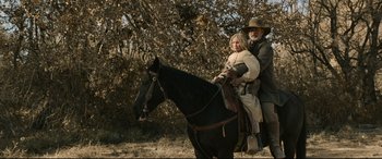 Movie still from “News of the World” (2020), directed by Paul Greengrass – A man and a woman on a horse in a field; Wide shot, Low angle