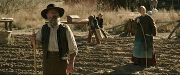 Movie still from “News of the World” (2020), directed by Paul Greengrass – An old man with a long beard is standing in the dirt; Medium shot, Over the shoulder angle