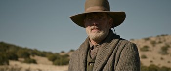 Movie still from “News of the World” (2020), directed by Paul Greengrass – An old man with a beard wearing a hat; Medium shot, Low angle