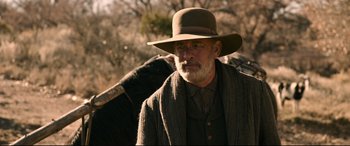 Movie still from “News of the World” (2020), directed by Paul Greengrass – An older man wearing a hat and a scarf; Medium shot, Over the shoulder angle