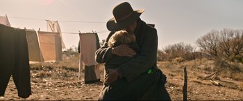 Movie still from “News of the World” (2020), directed by Paul Greengrass – An old man holding a young child in a field; Medium shot, Over the shoulder angle