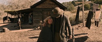 Movie still from “News of the World” (2020), directed by Paul Greengrass – A man and a woman standing next to each other in front of a log cabin; Wide shot, Over the shoulder angle