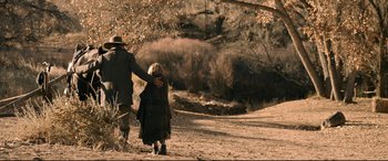 Movie still from “News of the World” (2020), directed by Paul Greengrass – An older man and a young girl walking on a dirt road; Wide shot, High angle