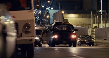 Movie still from “Nick and Norah's Infinite Playlist” (2008), directed by Peter Sollett – A black suv driving down a street at night; Extreme Wide shot, Over the shoulder angle