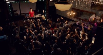 Movie still from “Nick and Norah's Infinite Playlist” (2008), directed by Peter Sollett – A group of people gathered in a large room; Extreme Wide shot, High angle