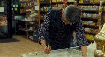 Movie still from “Nick and Norah's Infinite Playlist” (2008), directed by Peter Sollett – An older man writing on a piece of paper in a store; Medium shot, Low angle