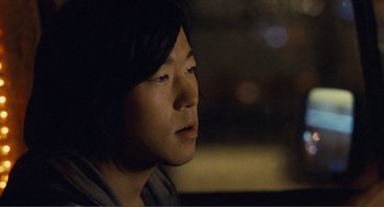 Movie still from “Nick and Norah's Infinite Playlist” (2008), directed by Peter Sollett – A young man sitting in a car at night looking out the window; Close Up shot, Over the shoulder angle