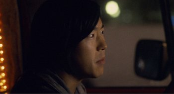 Movie still from “Nick and Norah's Infinite Playlist” (2008), directed by Peter Sollett – A person sitting in a room with a light on; Close Up shot, Over the shoulder angle