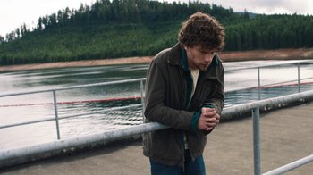 Movie still from “Night Moves” (2013), directed by Kelly Reichardt – A man standing next to a body of water; Medium shot, High angle