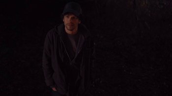 Movie still from “Night Moves” (2013), directed by Kelly Reichardt – A man standing in the dark with his hands in his pockets; Medium shot, High angle