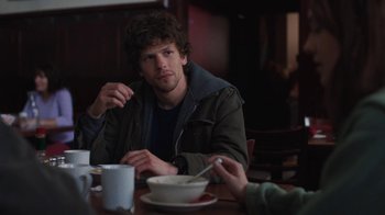 Movie still from “Night Moves” (2013), directed by Kelly Reichardt – A man sitting at a table with a bowl of food; Medium shot, Over the shoulder angle