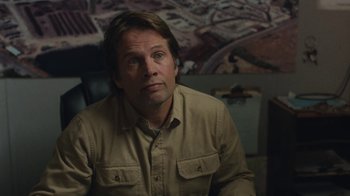 Movie still from “Night Moves” (2013), directed by Kelly Reichardt – A person sitting in a room; Close Up shot, Over the shoulder angle