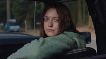 Movie still from “Night Moves” (2013), directed by Kelly Reichardt – A woman sitting in the back seat of a car; Medium shot, Over the shoulder angle