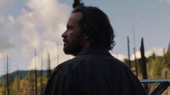 Movie still from “Night Moves” (2013), directed by Kelly Reichardt – A man with long hair and a beard is looking into the distance; Close Up shot, Low angle
