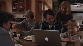 Movie still from “Night Moves” (2013), directed by Kelly Reichardt – A group of people sitting at a table with a laptop computer; Medium shot, Over the shoulder angle