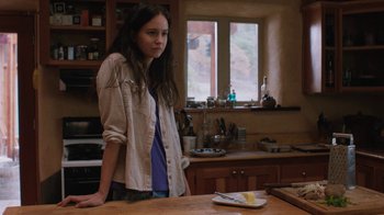 Movie still from “Night Moves” (2013), directed by Kelly Reichardt – A young woman standing in a kitchen next to a counter; Medium shot, Over the shoulder angle