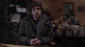 Movie still from “Night Moves” (2013), directed by Kelly Reichardt – A man sitting at a wooden table in a room; Medium shot, Over the shoulder angle