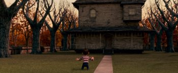 Movie still from “Monster House” (2006), directed by Gil Kenan – A little boy that is standing in the grass near a house; Wide shot, Low angle