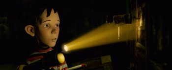 Movie still from “Monster House” (2006), directed by Gil Kenan – A boy is holding a flashlight in a dark room; Medium shot, Low angle