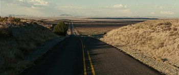 Movie still from “No Country for Old Men” (2007), directed by Joel Coen – An empty road in the middle of a desert landscape; Extreme Wide shot, High angle