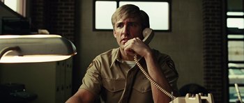 Movie still from “No Country for Old Men” (2007), directed by Joel Coen – A man talking on a phone while sitting in a chair; Close Up shot, Low angle