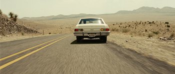Movie still from “No Country for Old Men” (2007), directed by Joel Coen – A car driving down the middle of a road; Wide shot, Low angle
