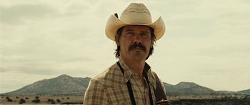 Movie still from “No Country for Old Men” (2007), directed by Joel Coen – A man in a cowboy hat and a plaid shirt; Close Up shot, Low angle