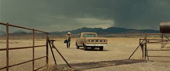 Movie still from “No Country for Old Men” (2007), directed by Joel Coen – A man standing next to an old pick - up truck; Extreme Wide shot, Low angle