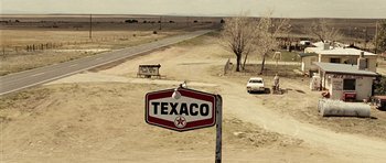 Movie still from “No Country for Old Men” (2007), directed by Joel Coen – An old texaco sign in the middle of a dirt road; Extreme Wide shot, High angle