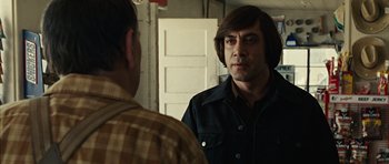 Movie still from “No Country for Old Men” (2007), directed by Joel Coen – A man in a plaid shirt looking at himself in the mirror; Close Up shot, Over the shoulder angle