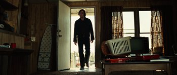 Movie still from “No Country for Old Men” (2007), directed by Joel Coen – A man walking in a doorway of a house; Wide shot, Low angle