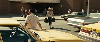 Movie still from “No Country for Old Men” (2007), directed by Joel Coen – A man in a cowboy hat walking down the street; Wide shot, Over the shoulder angle