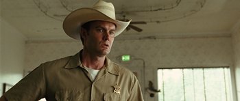 Movie still from “No Country for Old Men” (2007), directed by Joel Coen – A man wearing a cowboy hat and a sheriff's badge; Close Up shot, Low angle