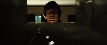 Movie still from “No Country for Old Men” (2007), directed by Joel Coen – A man in a hood stares at the camera; Close Up shot, Low angle