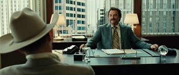 Movie still from “No Country for Old Men” (2007), directed by Joel Coen – A man sitting at a desk in front of a window; Medium shot, Over the shoulder angle