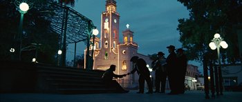 Movie still from “No Country for Old Men” (2007), directed by Joel Coen – A group of people standing on the steps in front of a church; Extreme Wide shot, Low angle