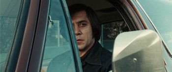 Movie still from “No Country for Old Men” (2007), directed by Joel Coen – A man sitting in the driver's seat of a car; Close Up shot, Low angle