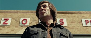 Movie still from “No Country for Old Men” (2007), directed by Joel Coen – A man in a denim jacket looking up at the sky; Close Up shot, Low angle