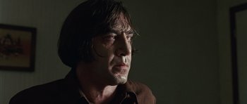 Movie still from “No Country for Old Men” (2007), directed by Joel Coen – A person wearing a brown shirt; Close Up shot, Low angle