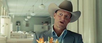 Movie still from “No Country for Old Men” (2007), directed by Joel Coen – A man wearing a cowboy hat holding a bouquet of flowers; Close Up shot, Over the shoulder angle