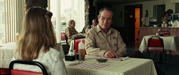 Movie still from “No Country for Old Men” (2007), directed by Joel Coen – An older man sitting at a table in a restaurant; Medium shot, Over the shoulder angle
