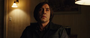 Movie still from “No Country for Old Men” (2007), directed by Joel Coen – A person wearing a black shirt; Close Up shot, Low angle