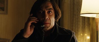 Movie still from “No Country for Old Men” (2007), directed by Joel Coen – A man talking on a phone while wearing a jacket; Close Up shot, Low angle