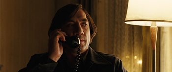 Movie still from “No Country for Old Men” (2007), directed by Joel Coen – A man talking on a phone while wearing a jacket; Close Up shot, Low angle
