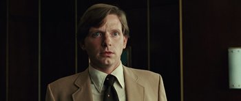 Movie still from “No Country for Old Men” (2007), directed by Joel Coen – A person wearing a suit and tie; Close Up shot, Low angle