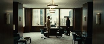 Movie still from “No Country for Old Men” (2007), directed by Joel Coen – Two men standing in front of a table in a room; Wide shot, Over the shoulder angle