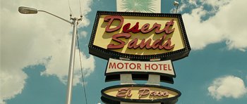 Movie still from “No Country for Old Men” (2007), directed by Joel Coen – A neon sign that reads desert sands motor hotel and el paso; Wide shot, Low angle