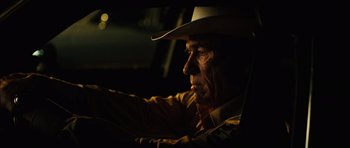 Movie still from “No Country for Old Men” (2007), directed by Joel Coen – A man wearing a cowboy hat sitting in a car; Close Up shot, Over the shoulder angle