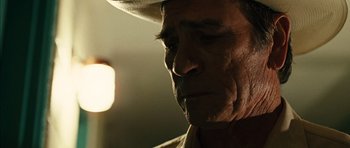 Movie still from “No Country for Old Men” (2007), directed by Joel Coen – An older man wearing a cowboy hat looking to his left; Close Up shot, Low angle